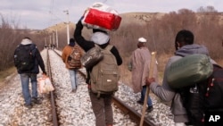 FILE - West African migrants walk on train tracks on their way to the Greek-Macedonian border near the town of Evzonoi, Greece, Feb. 28, 2015.