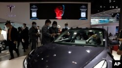 Visitors look at a Tesla Model 3 during the Shanghai Auto Show in Shanghai, April 21, 2021.