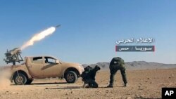 This May 25, 2017 photo provided by the government-controlled Syrian Central Military Media, shows Syrian government troops firing multiple launcher rockets at insurgent group's position in the Syrian province of Homs. 