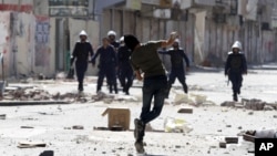 An anti-government protester throws a stone towards riot police during clashes in Daih, Bahrain, February. 14, 2013.