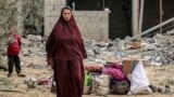 Uma mulher ao lado de objectos recuperados de edifício atingido durante a noite por bombardeamentos israelitas em Rafah, no sul da Faixa de Gaza, a 26 de março de 2024, no meio do conflito em curso no território palestiniano entre Israel e o grupo militante