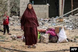 FILE— A woman stands by items that were salvaged from a building that was hit overnight during Israeli bombardment in Rafah in the southern Gaza Strip on March 26, 2024 amid the ongoing conflict in the Palestinian territory between Israel and Hamas.