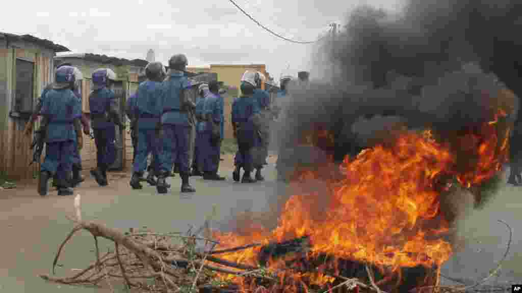 La police anti-émeute burundaise, en patrouille, dépasse un pneu en flamme que des manifestant ont brulé sur une rue de la capitale Bujumbura, Burundi, dimanche&nbsp;26 avril 2015. 