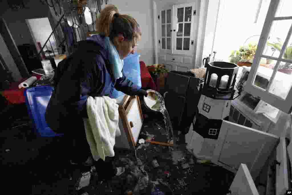 Kerrie Nocella mengeluarkan air laut dari barang-barang di rumah orangtuanya di Babylon Village, New York.