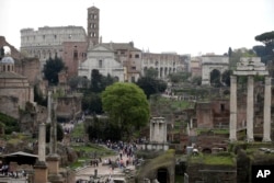 FILE - Tourists visit the ancient Roman forum and the Colosseum in Rome, April 17, 2015.