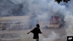 Amidst tear gas, a young man carries stones during a protest in Port-au-Prince, Haiti, September 14, 2011.
