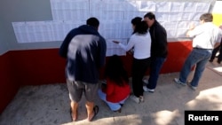 Citizens look for their names outside a public school before voting in nationwide congressional elections in Buenos Aires October 27, 2013.