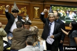 FILE - Julio Ygarza, left, Nirma Guarulla, center, and Romel Guzamana, deputies of the Venezuelan coalition of opposition parties, celebrate after their swearing-in ceremony during a session of the National Assembly in Caracas, Jan. 6, 2016.