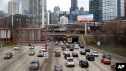 FILE - Traffic flows along Interstate 90 as a suburban commuter train moves along an elevated track in Chicago, Illinois, March 31, 2021. More than 20,000 traffic fatalities have been recorded in the first six months of 2021.