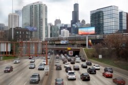 FILE - Traffic flows along Interstate 90 as a suburban commuter train moves along an elevated track in Chicago, Illinois, March 31, 2021.