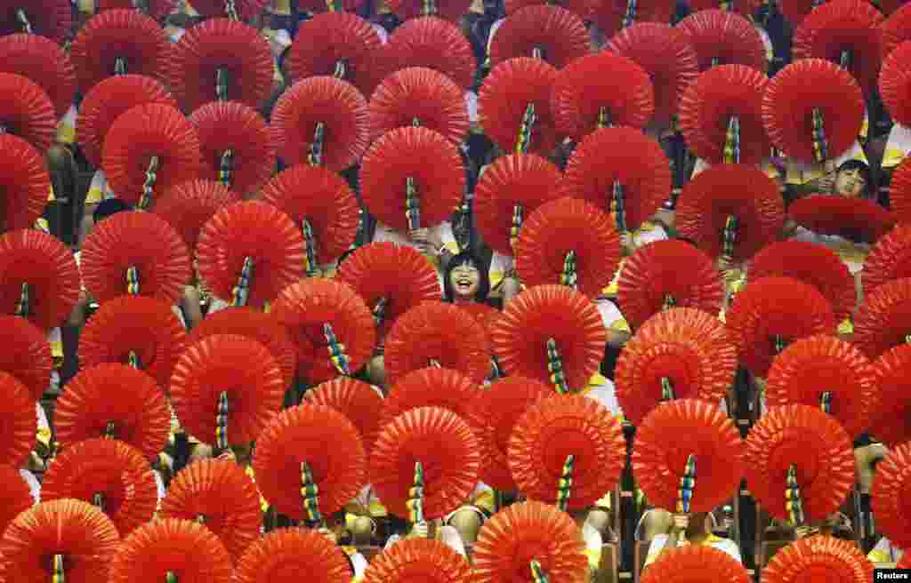 A girl laughs as she sits among hand fans during a mass performance at a children's martial arts fair in Foshan, Guangdong province.