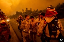 Firefighters discuss plans while battling the Carr Fire in Shasta, Calif., July 26, 2018.