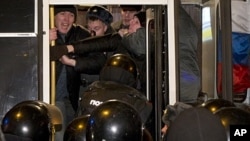 Russian police officers push detained opposition activists inside a police bus during an unsanctioned rally in downtown Moscow, December 31, 2011.