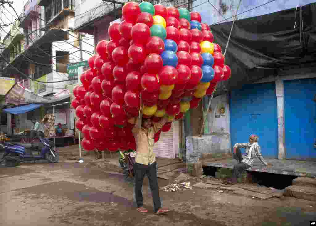 An Indian balloon seller carries loads of balloons, purchased from a whole seller to be sold in a market, in Allahabad, India.