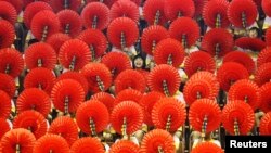 A girl laughs as she sits among hand fans during a mass performance at a children's martial arts fair in Foshan, Guangdong province, May 31, 2013. 