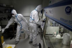 French lab scientists in protective suits work on developing a quick test for detecting the coronavirus, at Pasteur Institute in Paris, France, Feb. 6, 2020.