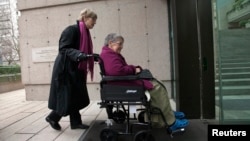 FILE - Gloria Taylor (R) enters the B.C Supreme Court with the help of Lee Carter, a fellow plaintiff in the case challenging the law regarding assisted-suicide in Vancouver, British Columbia on Dec. 1, 2011. Canada is announcing a new assisted-suicide law Thursday.