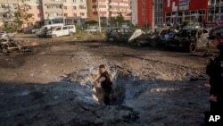 Un agente de policía extrae fragmentos de metralla de un cráter tras un ataque aéreo ruso en un barrio residencial de Sumy, Ucrania, el sábado 17 de agosto de 2024. 