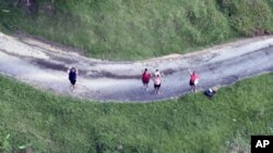 This photo made available by the U.S. Coast Guard shows residents near Utado, Puerto Rico, waiting for supplies to be dropped from the air, Oct. 3, 2017.