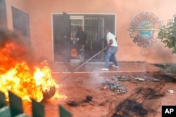 FILE — Workers put down a fire set at an office of Haiti's power company during a protest to demand the resignation of the Prime Minister Ariel Henry in Port-au-Prince, Haiti, March 1, 2024.