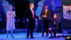 In this photo provided by The Public Theater, Tina Benko, left, portrays Melania Trump in the role of Caesar's wife, Calpurnia, and Gregg Henry, center left, portrays President Donald Trump in the role of Julius Caesar during a dress rehearsal of The Public Theater's Free Shakespeare in the Park production of Julius Caesar, in New York. Rounding out the cast on stage is Teagle F. Bougere as Casca, and Elizabeth Marvel, right, as Marc Anthony. (Joan Marcus/The Public Theater via AP)