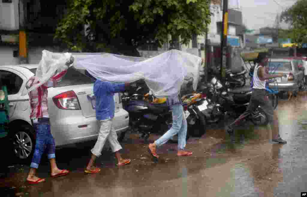 Indian men cover themselves with a plastic sheet as it rains in New Delhi, India. The monsoon rains which usually hit India from June to September are crucial for farmers whose crops feed hundreds of millions of people.