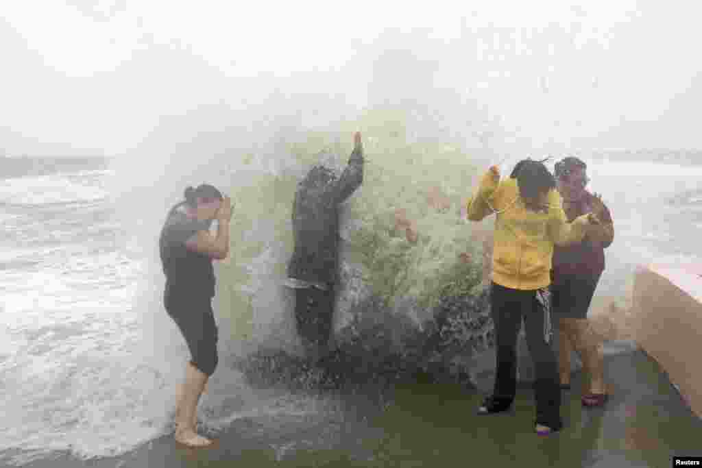 2012年10月29日，在飓风桑迪逼近当地之际，德妮特.萨纳科娃、亚伯拉罕.罗伯勒斯、劳拉.卡拉斯科和玛丽林.罗德里格斯(从左至右)在康涅狄克州米尔福德的岸边戏浪。
