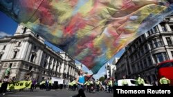 An Extinction Rebellion climate activist waves a large flag during a "peaceful disruption" of British Parliament as lawmakers return from the summer recess, in London, Sept. 1, 2020.