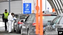 FILE - A member of the medical staff measures the temperature of a traveler at a autobahn park place near Gries am Brenner, Austrian province of Tyrol, at border crossing with Italy, March 10, 2020. 