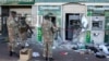 Des militaires inspectent des distributeurs automatiques de billets endommagés à l'extérieur d'une banque à Soweto, en Afrique du Sud, le 13 juillet 2021. 