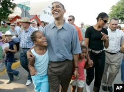 In this Aug. 16, 2007, file photo, then-presidential candidate Barack Obama and his daughter Malia, left, wife Michelle, and daughter Sasha enjoy the midway at the Iowa State Fair in Des Moines, Iowa. (AP Photo/M. Spencer Green)