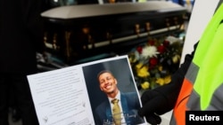 FILE — A mourner holds a photo near the coffin of Luke Fleurs, a South African footballer, during the funeral held at the New Apostolic Church in Mitchells Plain, Cape Town, on April 20, 2024.