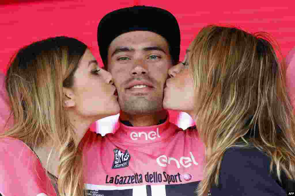 Two hostesses kiss Dutch cyclist Tom Dumoulin of Giant - Alpecin team as he bears the leader&#39;s pink jersey on the podium in the 7th stage of 99th Giro d&#39;Italia, Tour of Italy, from Sulmona to Foligno in Foligno, Italy.