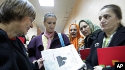 FILE - Human rights activist Natasa Kandic, left, reads a newspaper with family members of slain Bosnian Muslim men and boys at the Special Court building in Belgrade, Serbia, Dec. 21, 2005. 
