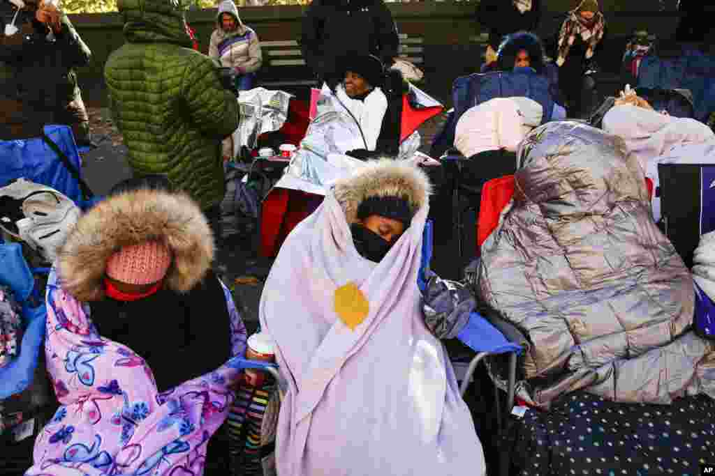 People try to stay warm as they wait for the start of the 92nd annual Macy&#39;s Thanksgiving Day Parade in New York.