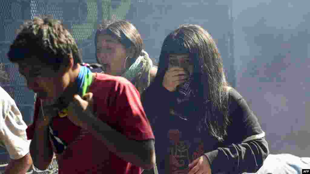 Estudiantes chilenos intentan escapar de una nube de gases lacrimógenos.