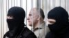 FILE - Oleksiy Pukach, former head of the surveillance department of Ukraine’s Interior Ministry, looks out from a defendant's cage during his trial in the murder of journalist Heorhiy Gongadze, in Kyiv, Ukraine, 29, 2013.
