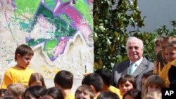 Former German Chancellor Helmut Kohl sits amid pupils next to a piece of the Berlin Wall next to his home in Ludwigshafen August 9, 2011.