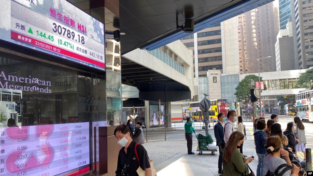 行人走过香港一家银行外的港股指数电子显示屏。(photo:VOA)