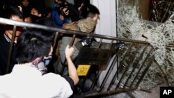 Masked pro-democracy protesters use a fence to try to break a glass window of the Legislative Council in Hong Kong early Nov. 19, 2014.