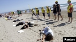 Amnesty International activists take part in a performance on a beach to commemorate World Refugee Day in Valencia, Spain, June 20, 2015. 