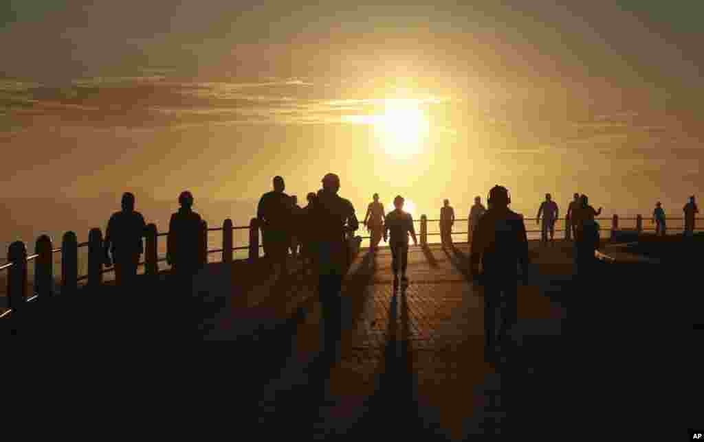 People exercise at sunrise in Sea Point, Cape Town, South Africa, as the country marks day 53 of a government lockdown in an effort to prevent the spread of coronavirus.