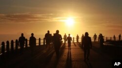 People exercise at sunrise in Sea Point, Cape Town, South Africa, as the country marks day 53 of a government lockdown in an effort to prevent the spread of coronavirus.