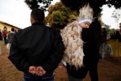 Jesus Cardozo Servin sleeps on his mother’s shoulder dressed in a feathered costume during a Mass in honor of St. Francis Solano in Emboscada, Paraguay, July 24, 2019.