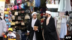 دو طلبه در حال قدم زدن در بازار مجاور حرم حضرت فاطمه معصومه در شهر قم در ایران. ۱۵ ژانویه ۲۰۱۹