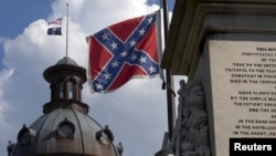 The U.S. flag and South Carolina state flag flies at half staff to honor the nine people killed in the Charleston murders as the confederate battle flag also flies on the grounds of the South Carolina State House in Columbia, SC, June 20, 2015.