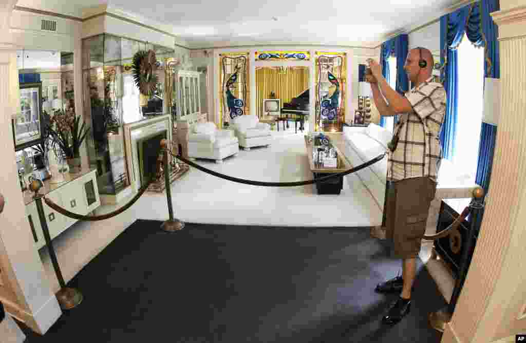 This Aug. 2010 photo shows a tourist viewing the living room at Graceland, Elvis Presley's home in Memphis, Tenn. Graceland opened for tours on June 7, 1982. They sold out all 3,024 tickets on the first day. 
