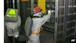 Workers wearing protective suits check the status of the water level indicator at the fuel area inside the crippled Fukushima Daiichi Nuclear Power Plant Number 1 reactor in Fukushima Prefecture May 10, 2011 in this handout photo released by TEPCO, May 12