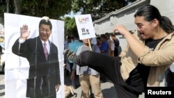 An activist kicks a portrait of Chinese President Xi Jinping during a protest against the upcoming meeting between Taiwan's President Ma Ying-jeou and Chinese President Xi Jinping, in front of the Presidential Office in Taipei, Taiwan, Nov. 5, 2015.