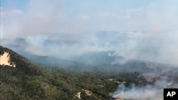 File- In this photo provided on Dec. 2, 2020, by the Queensland Fire and Emergency Services smoke blows over hills and toward the ocean at Fraser Island, Australia.